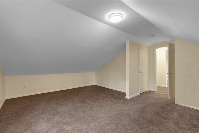 additional living space featuring lofted ceiling and dark carpet