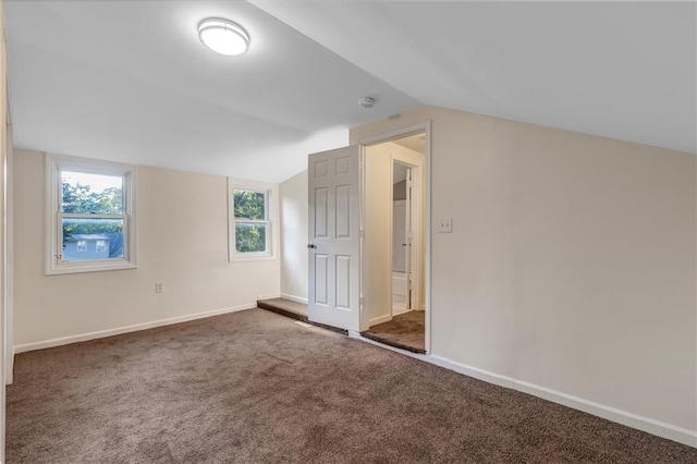 interior space with dark carpet and vaulted ceiling