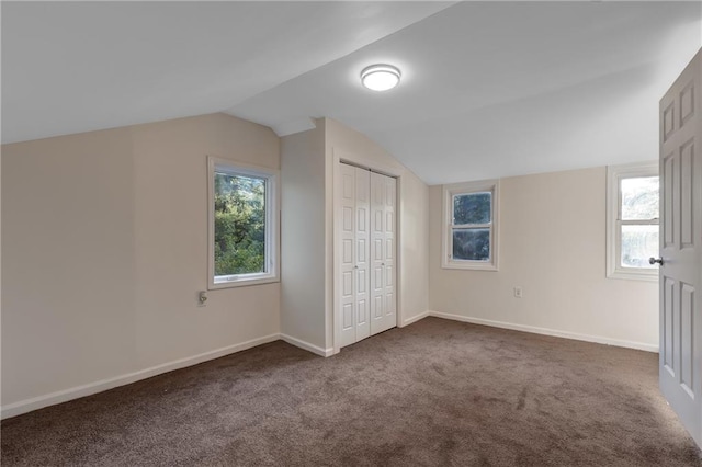 bonus room with lofted ceiling and dark carpet