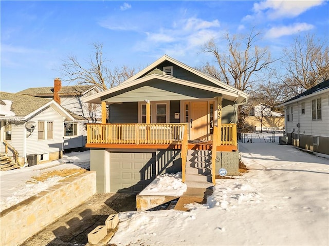 bungalow-style house with a garage, central air condition unit, and covered porch