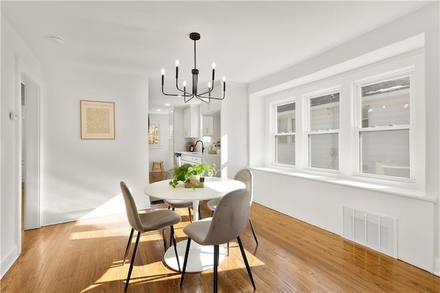 dining space featuring light wood-type flooring and a notable chandelier