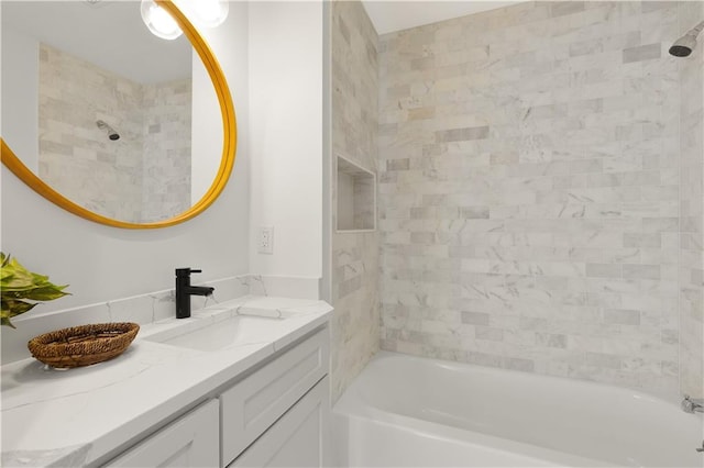 bathroom with tiled shower / bath combo and vanity