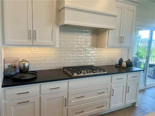 18300 Monrovia St, Overland Park, KS 66013 - kitchen with stainless steel gas stovetop, premium range hood, dark countertops, white cabinetry, and tasteful backsplash