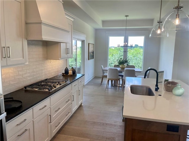 18300 Monrovia St, Overland Park, KS 66013 - kitchen with custom exhaust hood, stainless steel gas stovetop, a tray ceiling, decorative backsplash, and wood finished floors