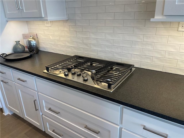 18300 Monrovia St, Overland Park, KS 66013 - kitchen view of stainless steel gas cooktop, dark countertops, white cabinets, backsplash, and dark wood-type flooring