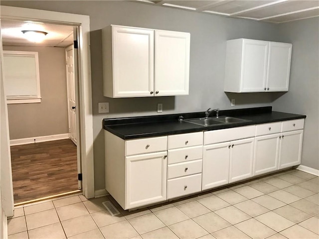 kitchen featuring light tile patterned floors, white cabinetry, and sink