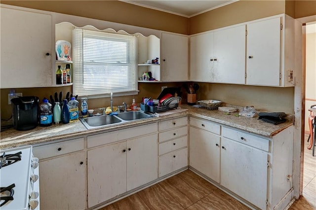 kitchen featuring white cabinets, gas range gas stove, sink, and crown molding