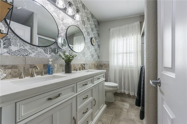 bathroom with toilet, vanity, and tile walls