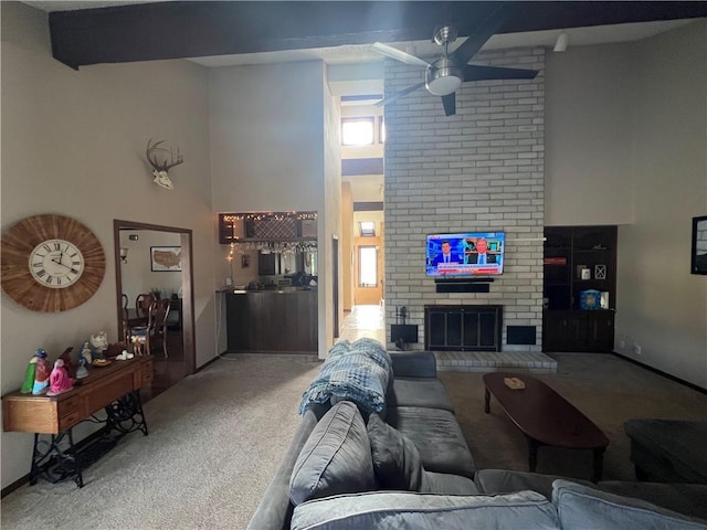 carpeted living room featuring a brick fireplace, ceiling fan, and a high ceiling