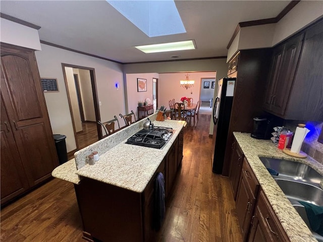 kitchen featuring ornamental molding, black appliances, dark wood-style floors, and a center island