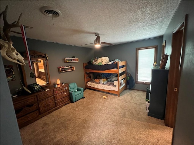 bedroom with a textured ceiling, visible vents, ceiling fan, and carpet