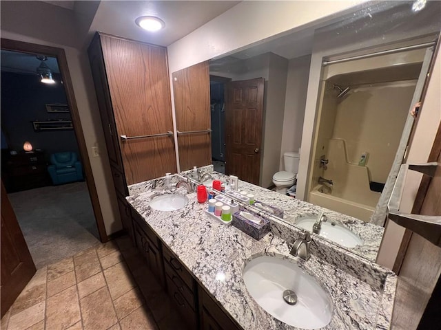 full bathroom with toilet, double vanity, and a sink