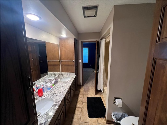 full bath featuring double vanity, a sink, baseboards, and visible vents