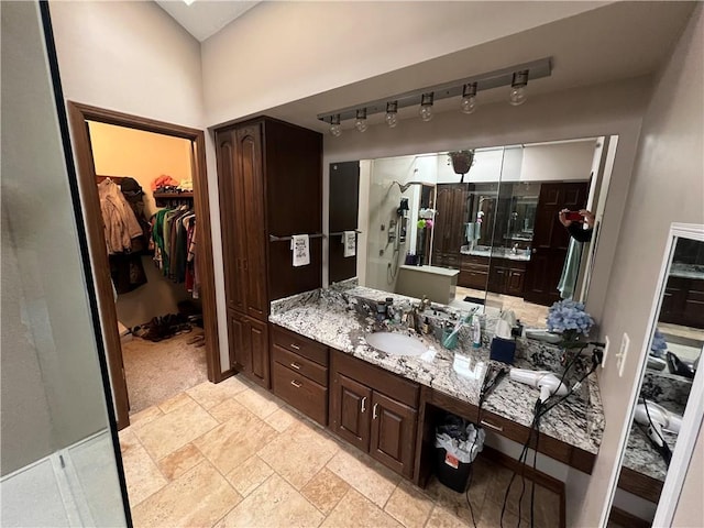 bathroom with stone tile flooring, vanity, and a spacious closet