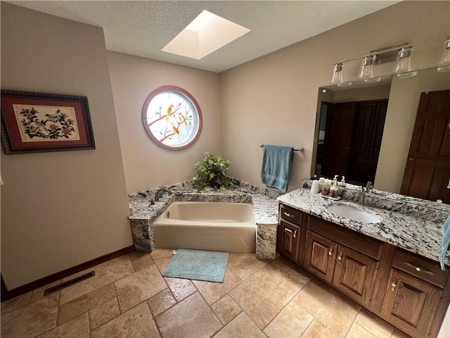 full bathroom with a skylight, stone tile flooring, a bath, vanity, and visible vents