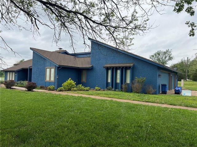 view of front of home featuring a garage, stucco siding, and a front yard