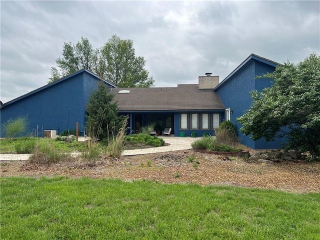 view of front of house with a front yard, a patio area, and a chimney