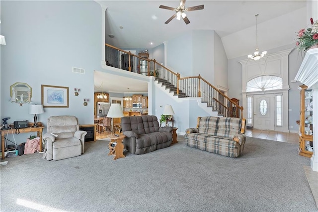 carpeted living room with ceiling fan with notable chandelier and high vaulted ceiling