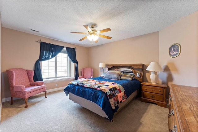 bedroom featuring ceiling fan, light colored carpet, and a textured ceiling