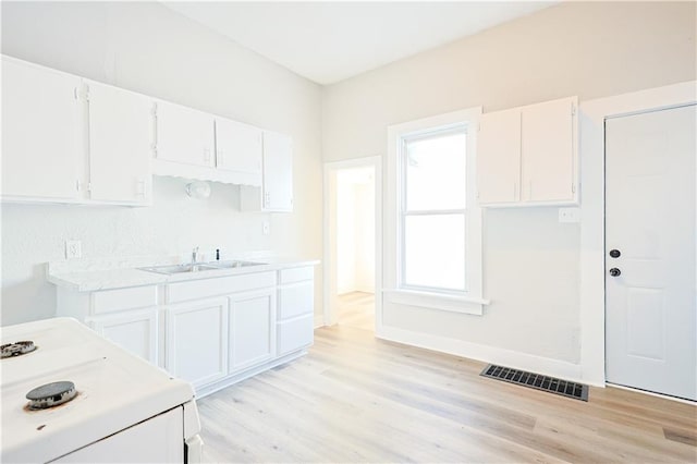 kitchen featuring white stove, sink, white cabinetry, and light hardwood / wood-style flooring