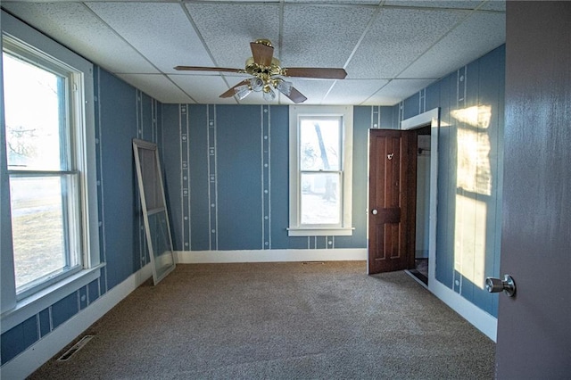 spare room featuring carpet floors, a wealth of natural light, a drop ceiling, and ceiling fan