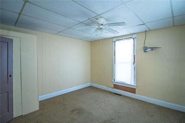 unfurnished room with ceiling fan, plenty of natural light, a drop ceiling, and carpet flooring