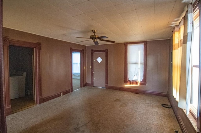 foyer entrance with ceiling fan, wood walls, and carpet flooring