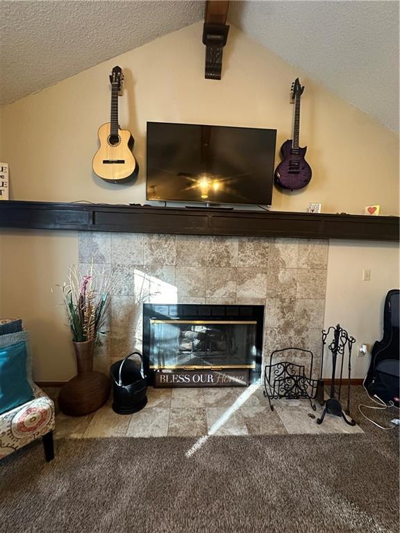 interior details with carpet, a tile fireplace, and a textured ceiling