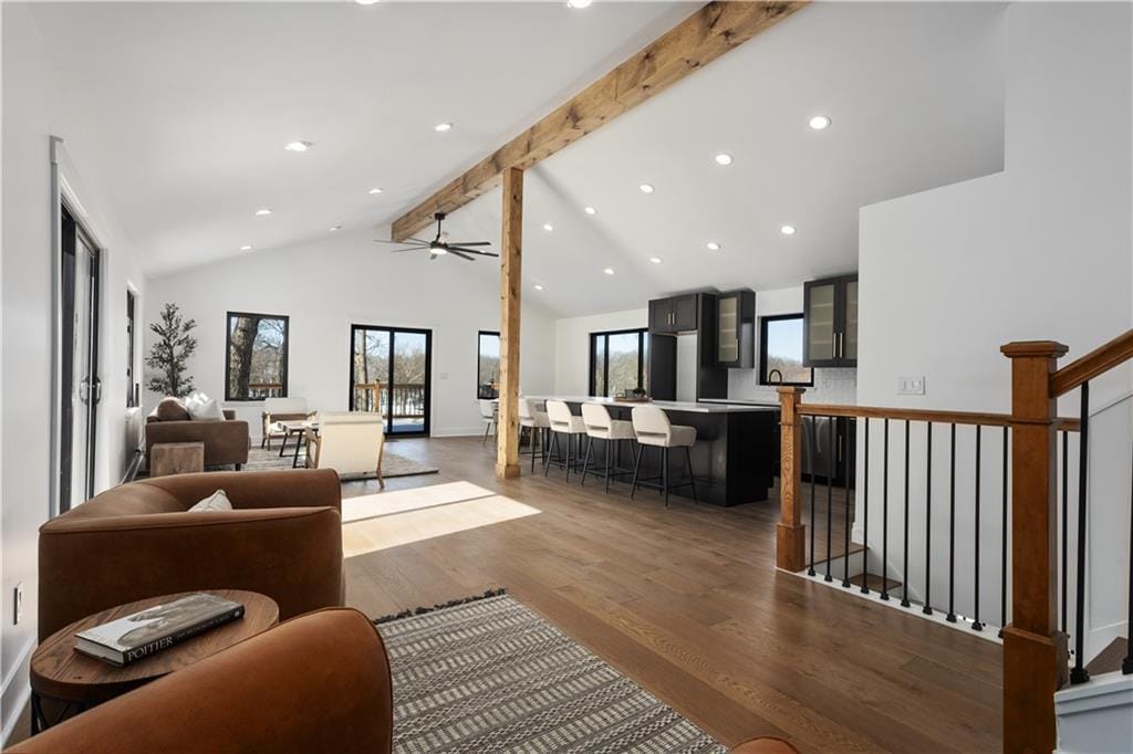 living room with ceiling fan, beam ceiling, hardwood / wood-style floors, and high vaulted ceiling