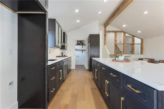 kitchen with stainless steel gas stovetop, light hardwood / wood-style floors, lofted ceiling with beams, refrigerator, and sink