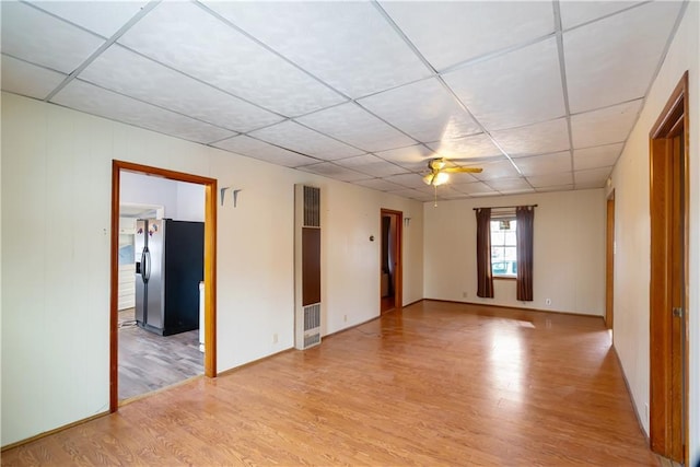 unfurnished room with ceiling fan, light hardwood / wood-style floors, and a drop ceiling