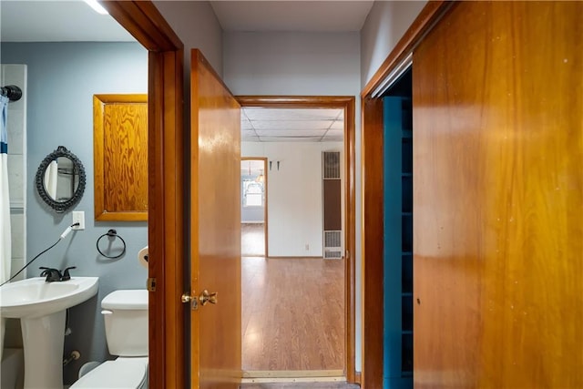 bathroom with toilet, wood-type flooring, and sink