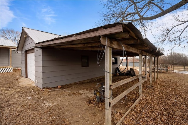 view of side of home featuring electric panel, a garage, a carport, and an outdoor structure