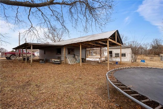 back of house with a trampoline and a carport