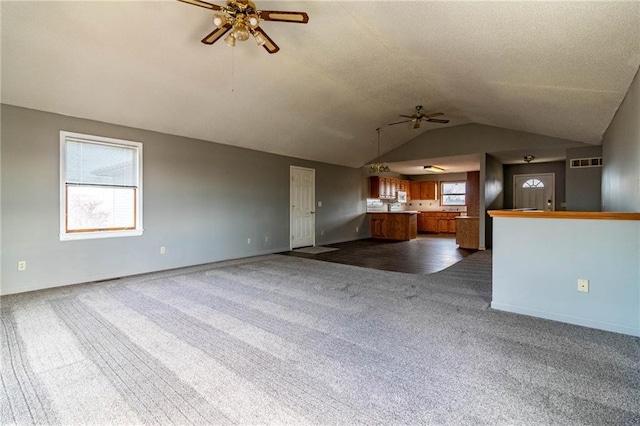 unfurnished living room featuring dark colored carpet, lofted ceiling, and ceiling fan