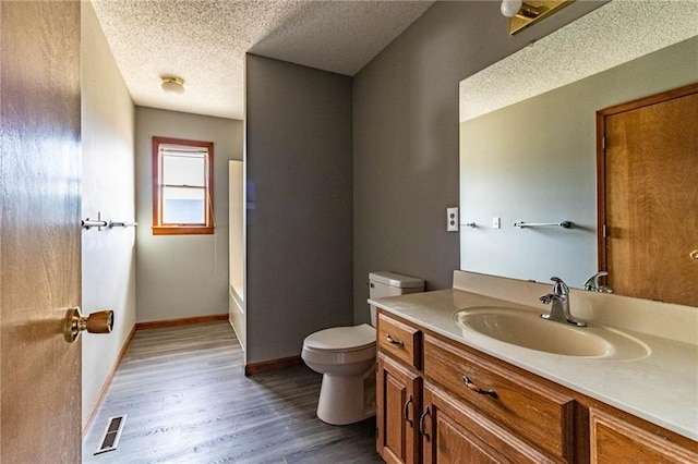 bathroom featuring vanity, hardwood / wood-style flooring, a textured ceiling, and toilet