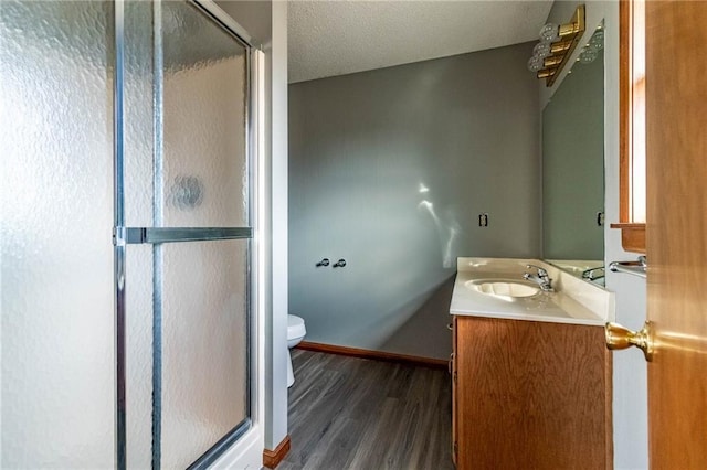 bathroom with vanity, hardwood / wood-style flooring, a shower with shower door, and toilet