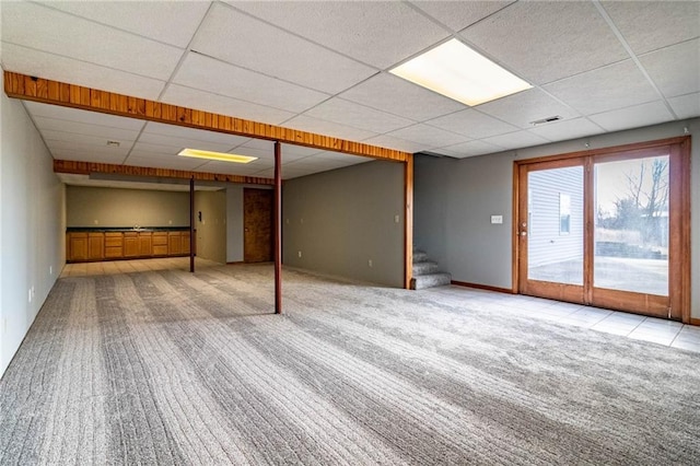 basement with a paneled ceiling and light colored carpet