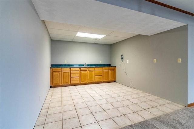 kitchen featuring light carpet and a paneled ceiling