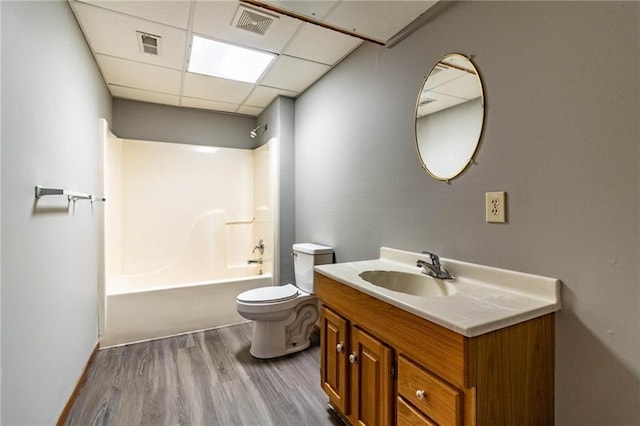 full bathroom featuring tub / shower combination, hardwood / wood-style floors, vanity, a drop ceiling, and toilet