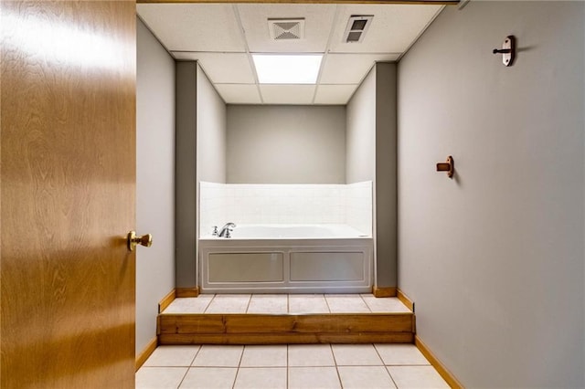 bathroom featuring a tub, a drop ceiling, and tile patterned floors