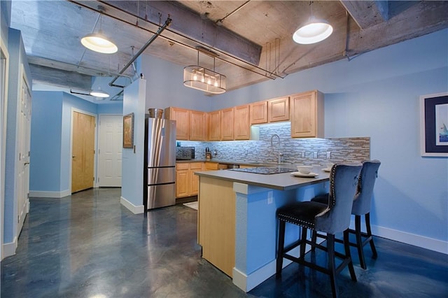 kitchen featuring light brown cabinetry, hanging light fixtures, stainless steel refrigerator, and kitchen peninsula