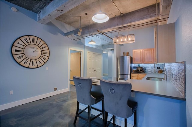 kitchen with sink, stainless steel refrigerator, backsplash, a kitchen breakfast bar, and kitchen peninsula