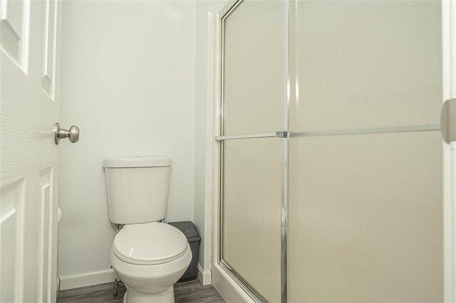 bathroom featuring an enclosed shower, wood-type flooring, and toilet