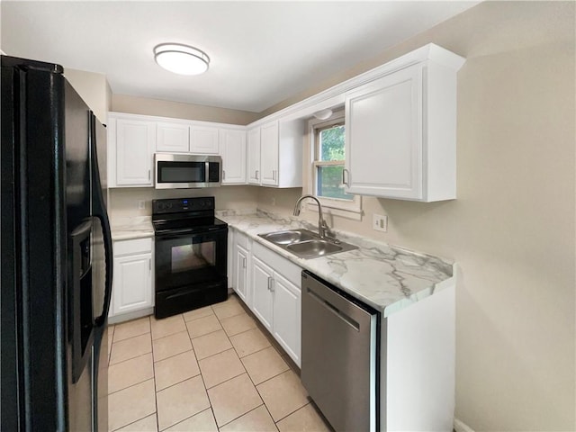 kitchen with light tile patterned floors, white cabinetry, light stone countertops, black appliances, and sink