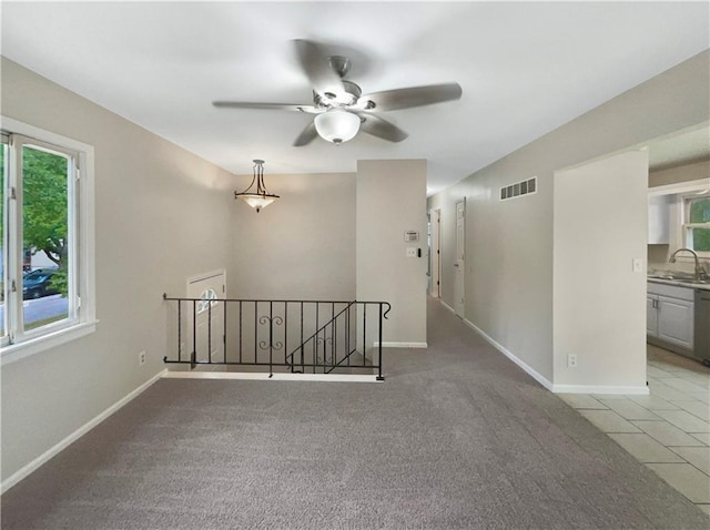 empty room featuring ceiling fan, light tile patterned flooring, and sink