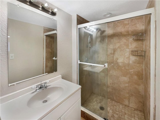 bathroom with a shower with shower door and vanity