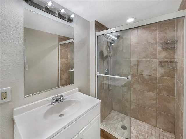 bathroom featuring a shower with shower door and vanity