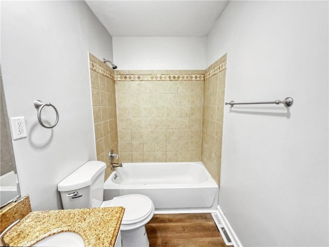 full bathroom featuring wood-type flooring, tiled shower / bath combo, vanity, and toilet