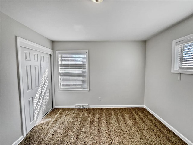 unfurnished bedroom featuring dark carpet and a closet